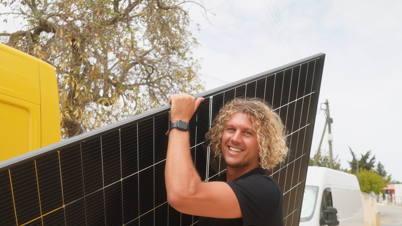 Founder carrying a solar panel in front of Voltaicos vans in the Algarve